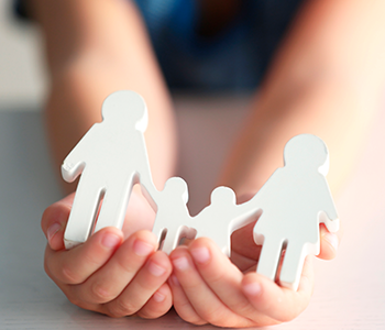 A person holds a paper cutout of a family