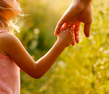 A little girl holds hands with her father